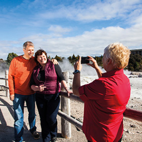 Guide taking picture of couple at geyser in Rotorua