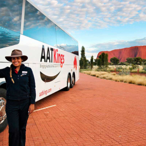 An AAT Kings coach tour in Australia with a tour guide stood next to the bus