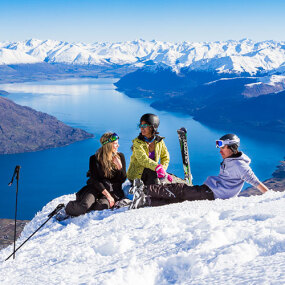 Skiers resting on the top of Remarkables ski field overlooking Queenstown