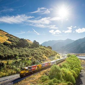 TranzAlpine train along side river bed in New Zealand Southern Alps mountain range