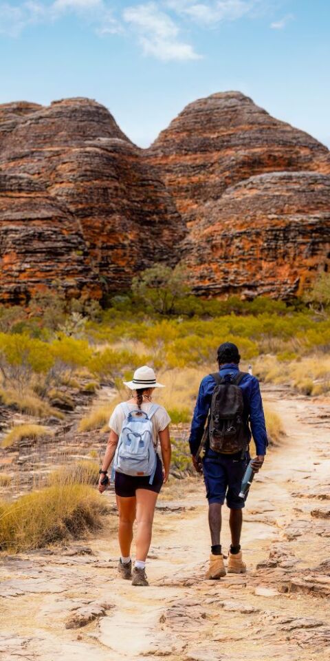 Aboriginal guide walking with woman - credit to tourism australia