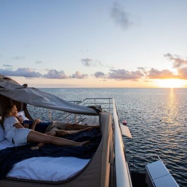 couple on a bed on a boat looking out to sea