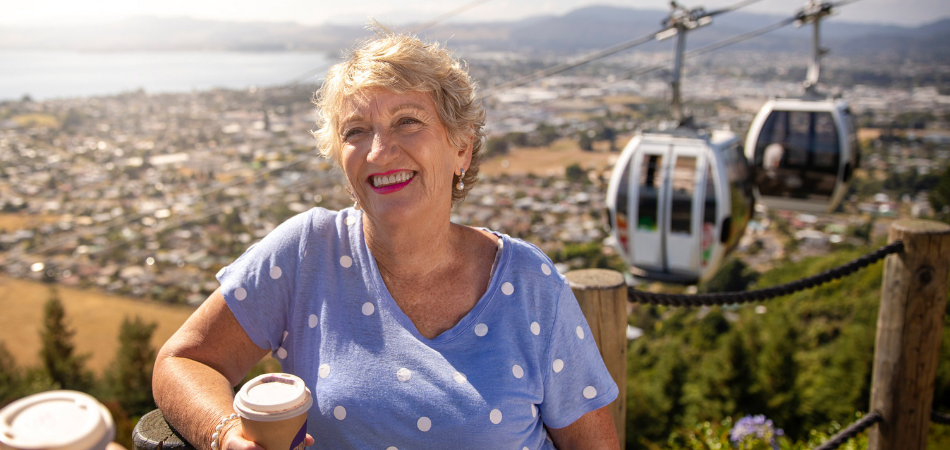 Senior solo traveler drinking coffee on Rotorua Skyline