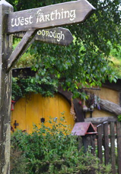 Wooden signposts and yellow Hobbit house at the back