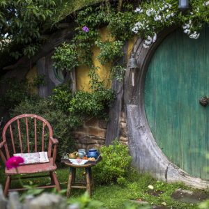 Circular green door surrounded by lush greenery and flowers at Hobbiton