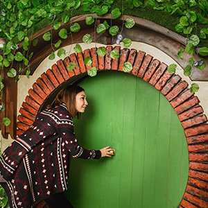 Woman exploring a Hobbit hole in Hobbiton, New Zealand