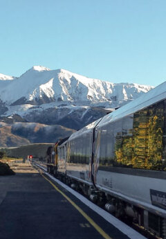 The TranzAlpine train waiting on the platform at Springfield with mountains in the background