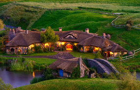 Hobbit house at dusk with the lights on