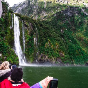 An AAT Kings' tour group photographs a waterfall cascading down a cliff.