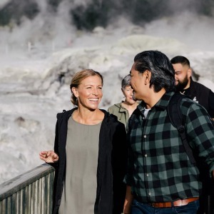 A smiling couple walks along a boardwalk at a geothermal site.