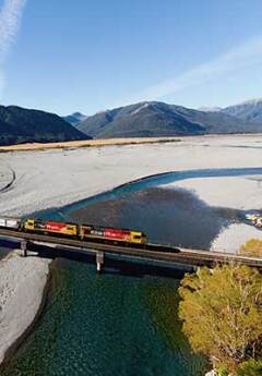 Tranzalpine crossing river and heading towards mountains on a sunny day