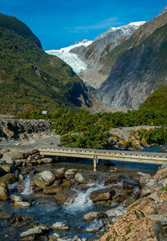 View of Franz Josef glacier and birdge crossing a river