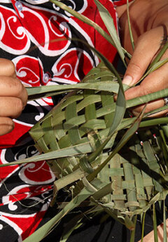 A Maori woman weaving a flax basket