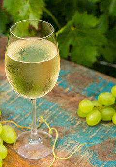 Image of a glass of white wine and green grapes
