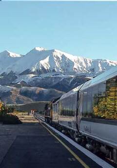 Tranzalpine train at the station and the snowcapped mountains in the back