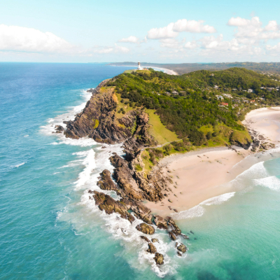 Turquoise waters with rocky coastline and lighthouse sitting on top of the hill