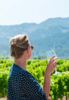 A lady tasting wine in Marlborough while looking out onto the vineyard