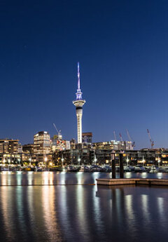 View of Auckland skyline, Sky Tower and city lights mirrored in the sea at night