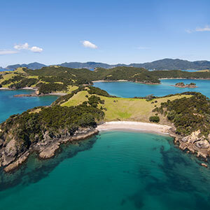 An aerial view of a small, sheltered beach with clear turquoise water and green islands.