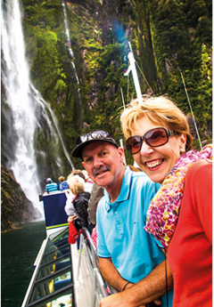 A cuple enjoying a view of waterfall in Milford Sound during AAT Kings coach tour