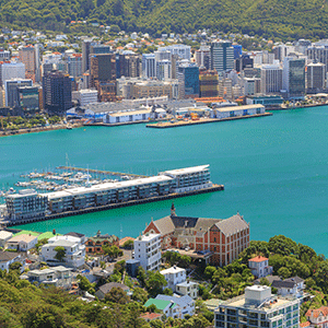 A view of the Wellington Harbour, the ocean water bright turquoise blue and framed in by the docks and large buildings.