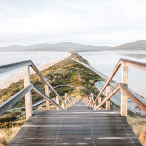 Wooden stairs leading down to a narrow coastal isthmus.