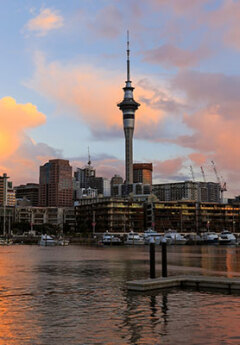 The Auckland skyline at sunset . Reflections of the sky tower on the water