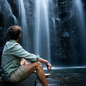 Person sitting in front of Ellinjaa Falls in the Atherton Tablelands