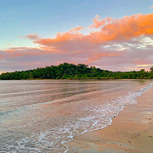 Gentle waves lap against the shore at sunset on Kewarra Beach, near Cairns