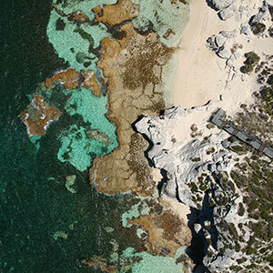 A birds eye view of the rocky shore meeting the emerald waters on Rottnest Island