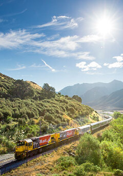 Tranzalpine train crossing the river and heading towards the mountains