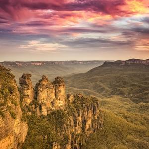 View of the Three Sisters rock formations in the canyon during a bright pink sunset