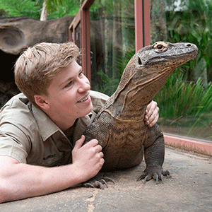 Robert Irwin lying next to a goanna at Australia Zoo