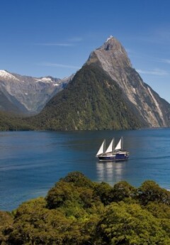 An aerial shot of the Milford Mariner cruising along Milford Sound, with Mitre Peak towering in the background.