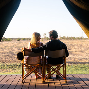 Two people sitting on a private deck, overlooking an expansive outdoor landscape