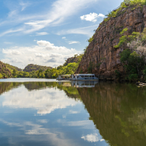 Two boats parked up on the river with a towering river cliff