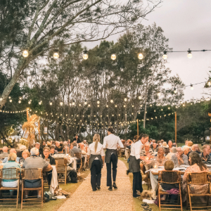 People sitting at a table with waiter serving and fairy lights above