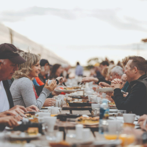 People eating at a table with food and drinks on the table
