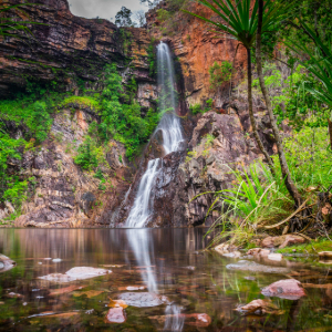 Water hole with water falling from red rocky cliffs
