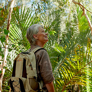 Woman with a backpack admiring lush green tropical surroundings.