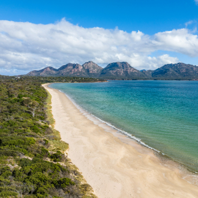 long beach with blue water and mountain range in the back
