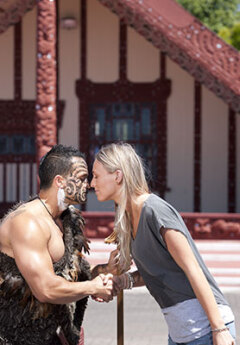 A Māori man performs a traditional hongi greeting with a woman.