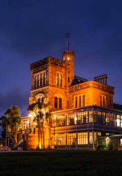 Larnach Castle illuminated in orange lights at nighttime