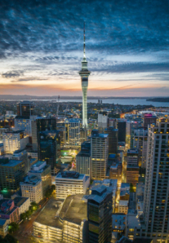 Sun rising with the city below lit up with many tall building and one tall building in the centre