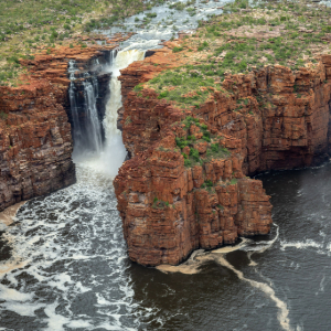 Dual waterfalls cascade between towering, rugged rock cliffs.