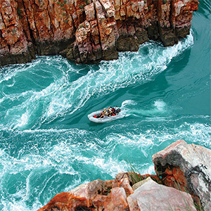 Inflatable boat navigating through churning water in a gorge.