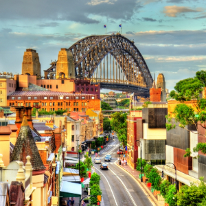 Sydney Harbour Bridge looms over a street with buildings.