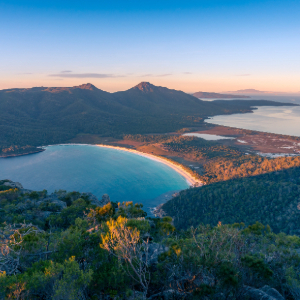 Panoramic view of a crescent-shaped bay at sunset.