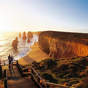 Wooden boardwalk overlooking ocean, cliffs, and limestone stacks.