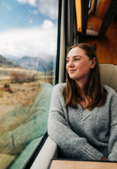 Passenger in window seat enjoying views from the TranzAlpine train.